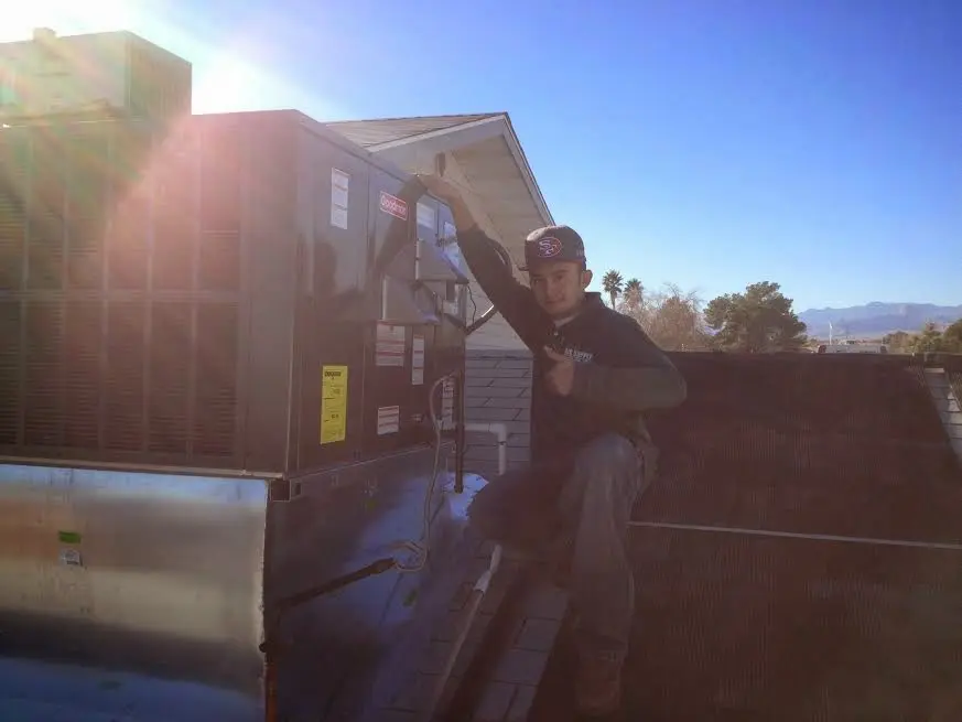 HVAC technician performing Air Duct Cleaning on a rooftop unit in Minot
